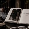 Fashion runway beside an open Saint Laurent book, showing how fashion brands turn books into part of their legacy by preserving collections and creative history.